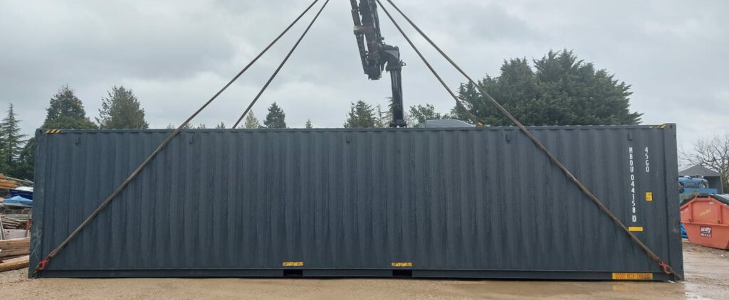 Container de stockage 40 pieds High Cube Double Doors en cours de levage par une grue pour Pury Paysagistes à Yverdon.