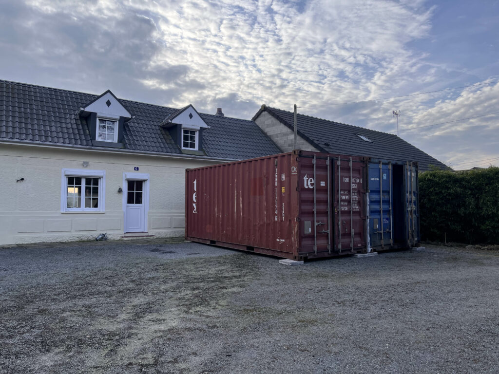 Deux containers de stockage, un rouge et un bleu, installés par In'Box Container devant une maison à Doullens pour un besoin de volume important durant une rénovation.