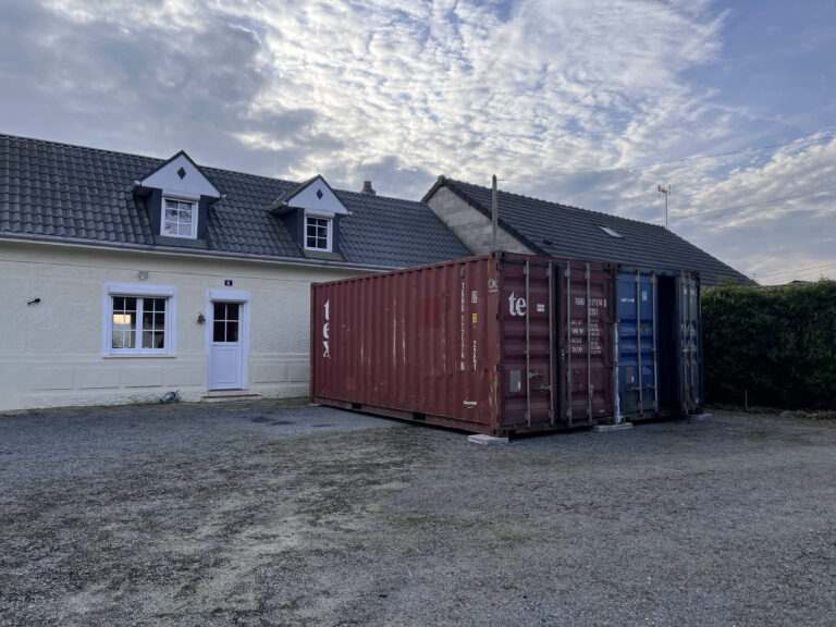 Deux containers de stockage, un rouge et un bleu, installés par In'Box Container devant une maison à Doullens pour un besoin de volume important durant une rénovation.
