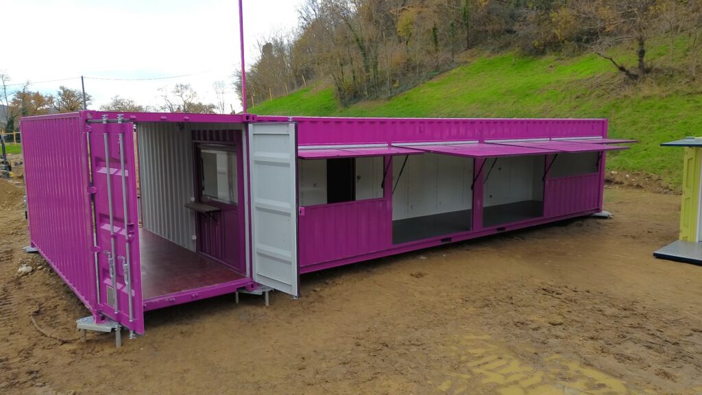 Assemblage de trois containers aménagés rose fuchsia par In'Box Container pour La Forêt des Champos au Lac de Champos : entrée 20 pieds à gauche et restauration 40 pieds à droite.