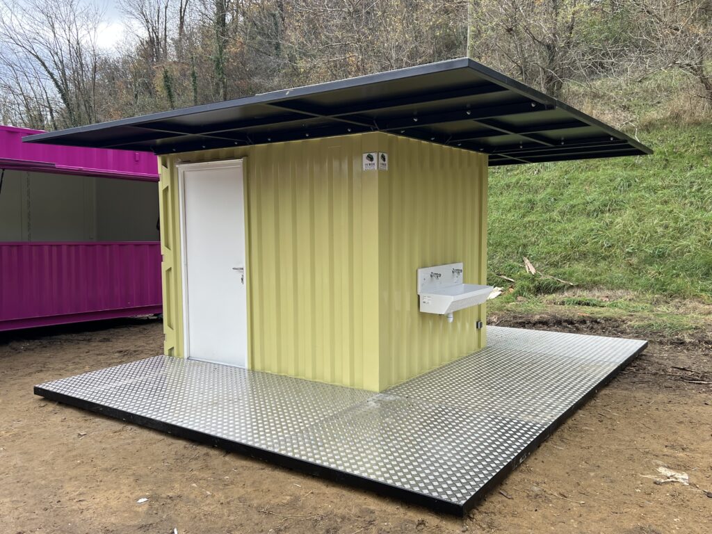 Container sanitaire 10 pieds jaune aménagé par In'Box Container pour La Forêt des Champos, vue extérieure avec lavabo au Lac de Champos.