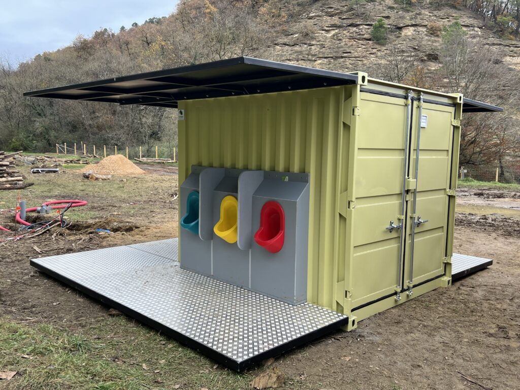 Urinoirs colorés (bleu, jaune, rouge) dans le container sanitaire 10 pieds jaune aménagé par In'Box Container pour La Forêt des Champos au Lac de Champos.