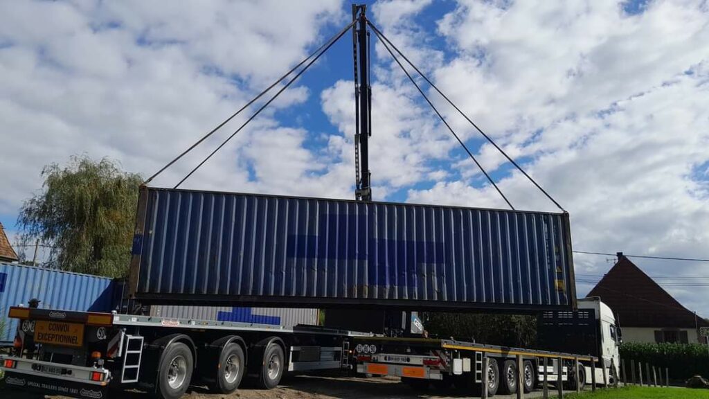Container maritime bleu de 40 pieds High Cube livré par camion grue pour un projet de maison container dans le Territoire de Belfort (90).