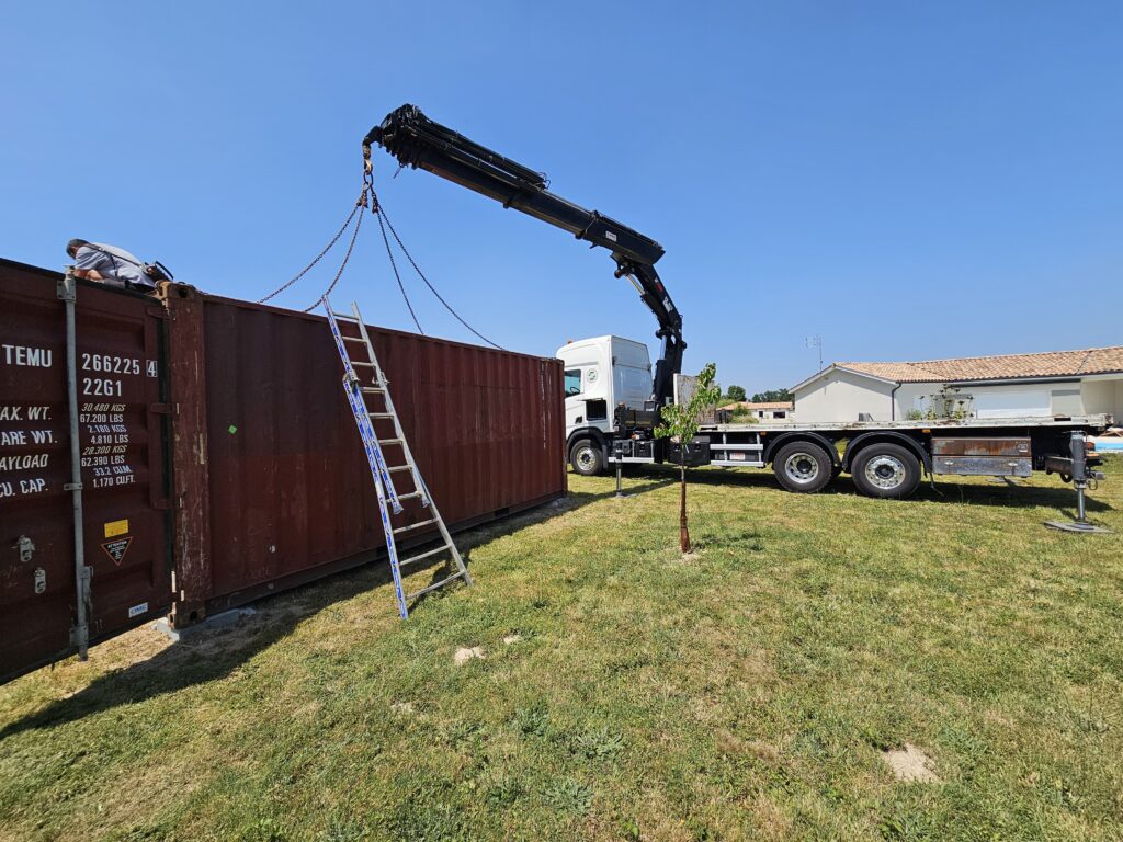 Grue hydraulique soulevant container TEMU 20 pieds installation terrain Ménesplet